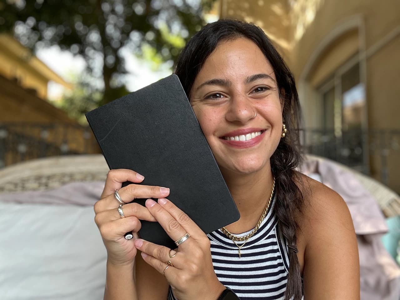 Me out on the balcony, holding the black notebook I draft each month’s letter in